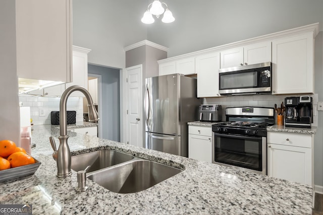 kitchen with sink, stainless steel appliances, white cabinets, and light stone countertops