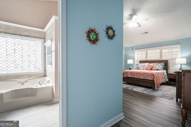 bedroom featuring hardwood / wood-style floors, a textured ceiling, and ceiling fan