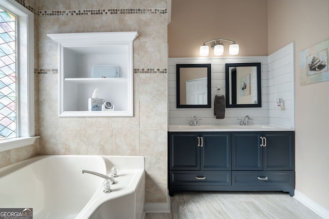 bathroom featuring a healthy amount of sunlight, tile walls, vanity, and a tub