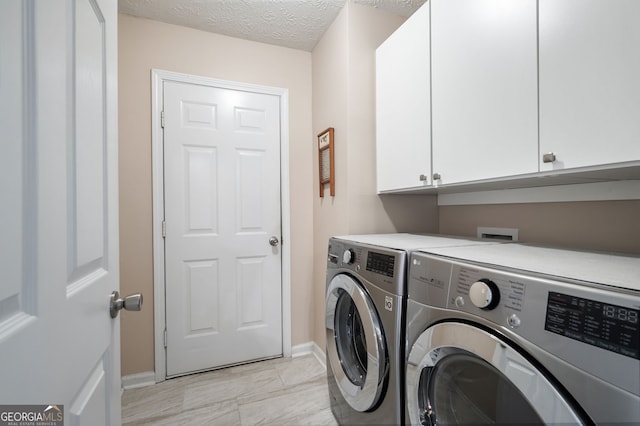 laundry area with cabinets, a textured ceiling, and washer and clothes dryer