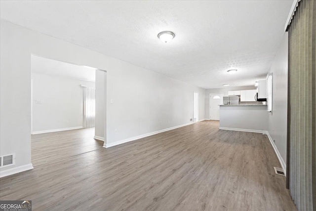 unfurnished living room featuring wood-type flooring and a textured ceiling