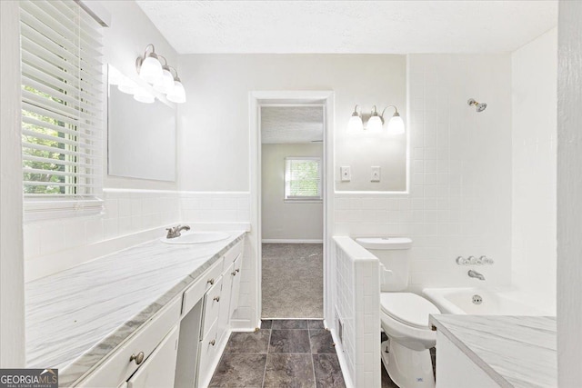 bathroom with vanity, tile walls, a textured ceiling, and toilet