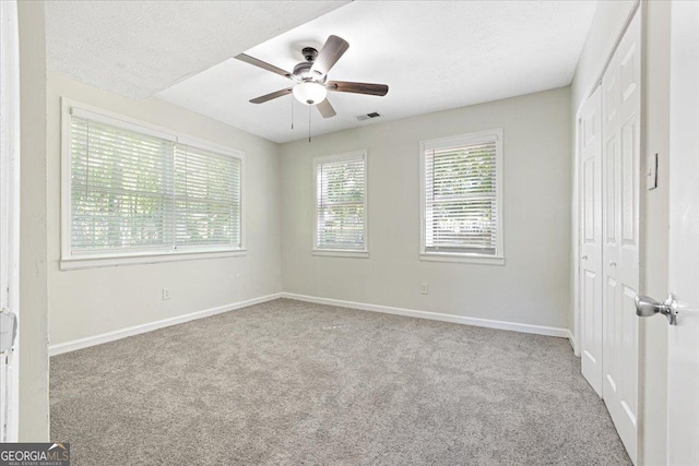 empty room featuring light carpet, ceiling fan, and a textured ceiling