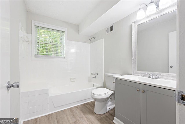 full bathroom featuring vanity, tiled shower / bath combo, wood-type flooring, and toilet