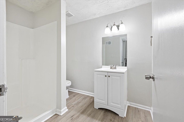 bathroom featuring wood-type flooring, vanity, a textured ceiling, and toilet