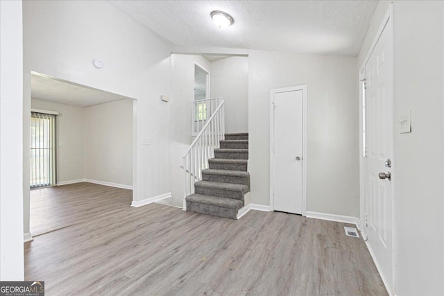 foyer entrance featuring light hardwood / wood-style flooring and a textured ceiling