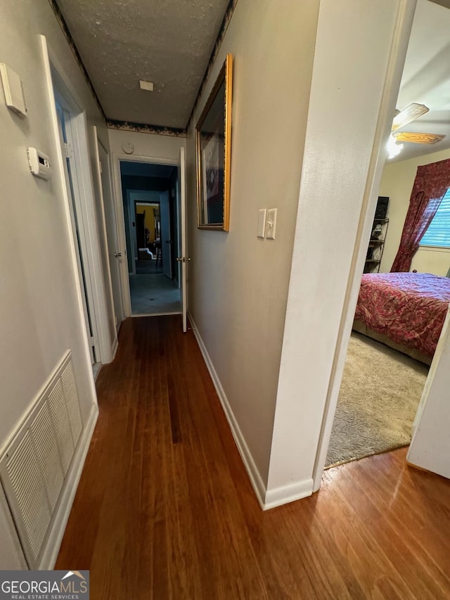 corridor with wood-type flooring and a textured ceiling