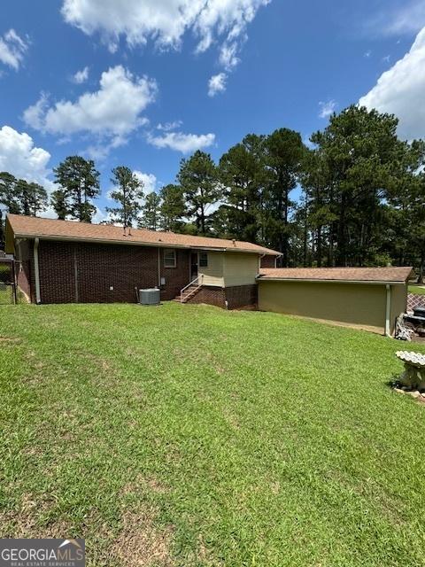 back of property featuring central AC unit and a lawn