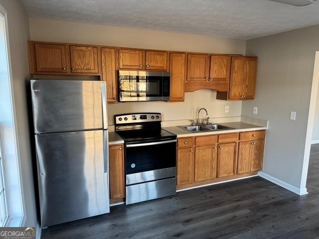 kitchen with dark hardwood / wood-style flooring, sink, stainless steel appliances, and a textured ceiling