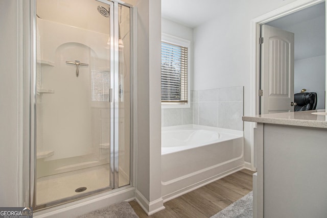 bathroom with vanity, hardwood / wood-style flooring, and plus walk in shower