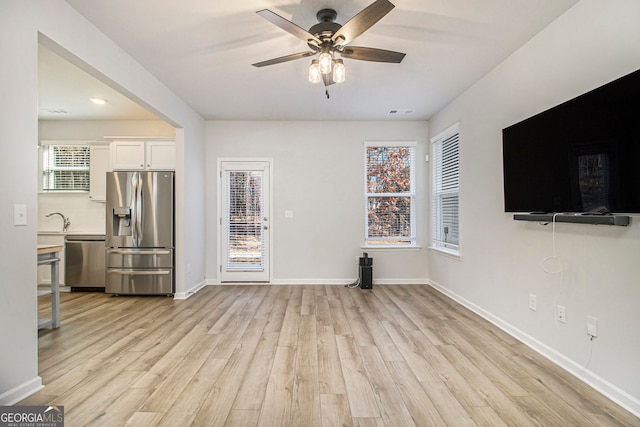 unfurnished living room with sink, light hardwood / wood-style floors, and ceiling fan