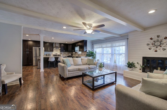 living room with dark hardwood / wood-style flooring, a textured ceiling, and beamed ceiling