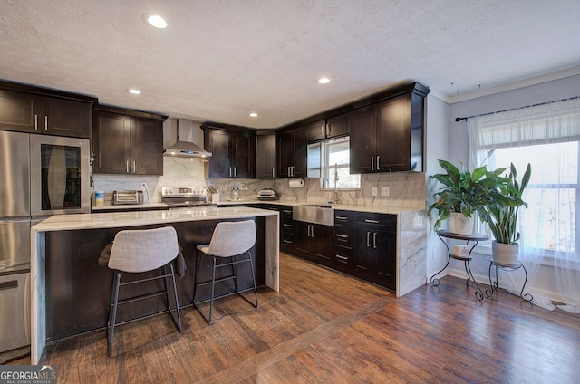 kitchen featuring wall chimney exhaust hood, stainless steel range with electric cooktop, tasteful backsplash, dark hardwood / wood-style flooring, and a kitchen island