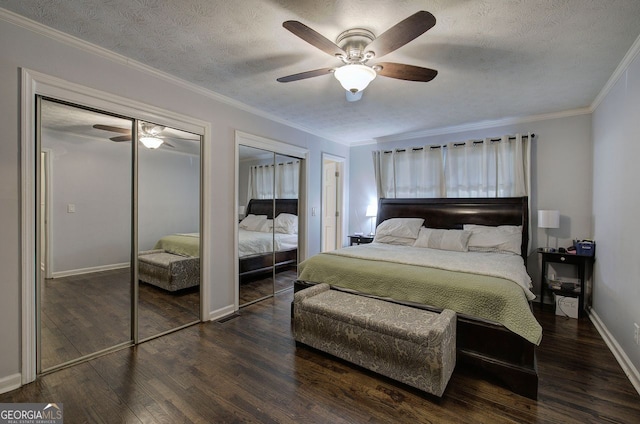 bedroom with dark wood-type flooring, crown molding, a textured ceiling, and two closets