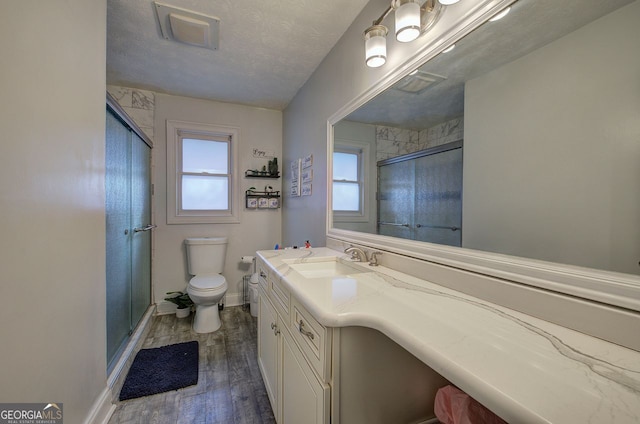 bathroom with toilet, an enclosed shower, a textured ceiling, vanity, and hardwood / wood-style flooring