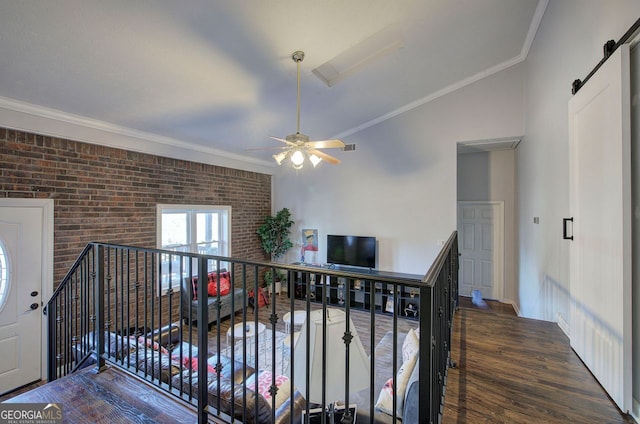 corridor with brick wall, crown molding, a barn door, and dark wood-type flooring