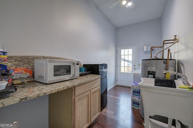 kitchen featuring vaulted ceiling, dark hardwood / wood-style floors, light brown cabinetry, sink, and electric water heater