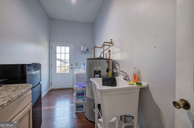 laundry room with sink, dark hardwood / wood-style floors, and electric water heater