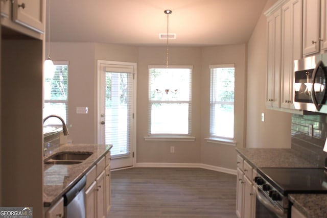 kitchen featuring stone counters, appliances with stainless steel finishes, pendant lighting, sink, and dark wood-type flooring