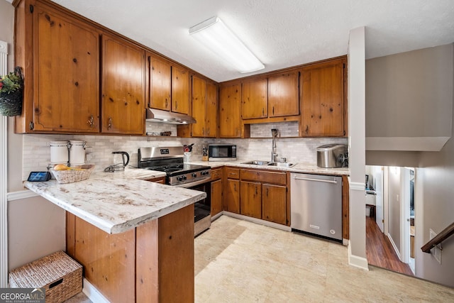 kitchen with sink, a kitchen breakfast bar, decorative backsplash, kitchen peninsula, and stainless steel appliances