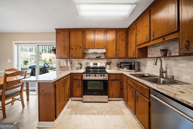 kitchen featuring sink, decorative backsplash, light stone counters, kitchen peninsula, and stainless steel appliances