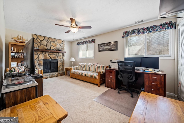 office featuring ceiling fan, light colored carpet, a fireplace, and a textured ceiling