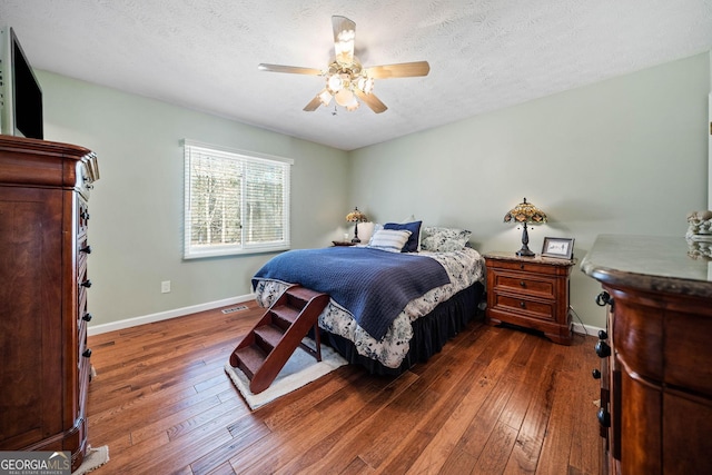 bedroom featuring ceiling fan, dark hardwood / wood-style floors, and a textured ceiling