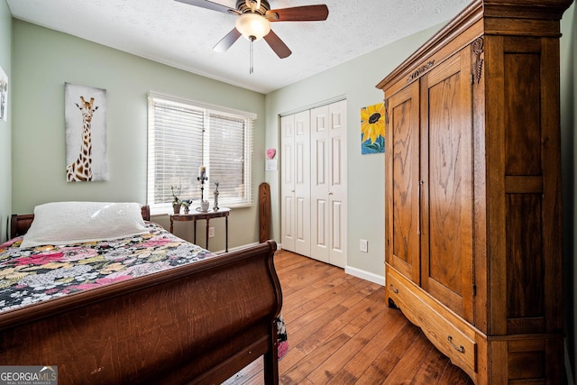 bedroom featuring ceiling fan, light hardwood / wood-style flooring, multiple closets, and a textured ceiling