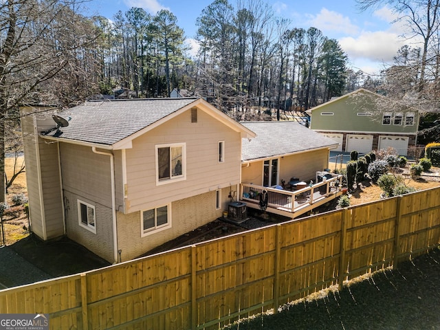 rear view of property featuring a garage, central AC unit, and a deck