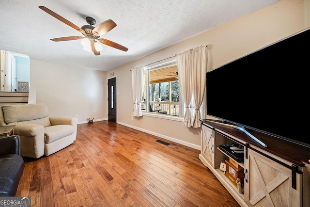 living room featuring hardwood / wood-style floors, a textured ceiling, and ceiling fan