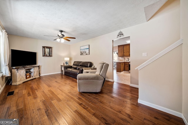 living room featuring hardwood / wood-style floors, a textured ceiling, and ceiling fan