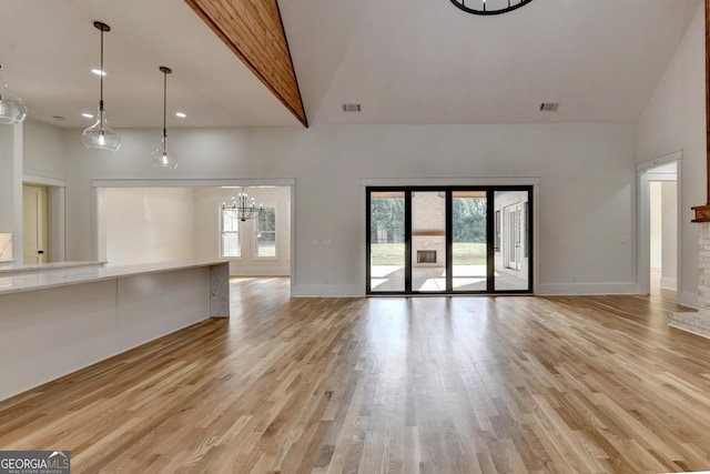 unfurnished living room with light wood-type flooring, a wealth of natural light, and high vaulted ceiling