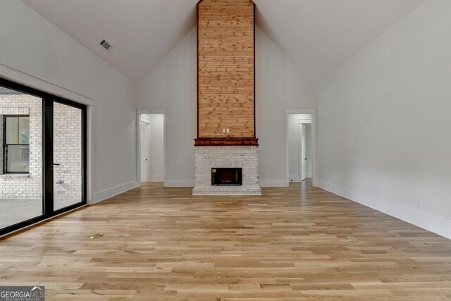 unfurnished living room featuring high vaulted ceiling, light wood-type flooring, and a fireplace