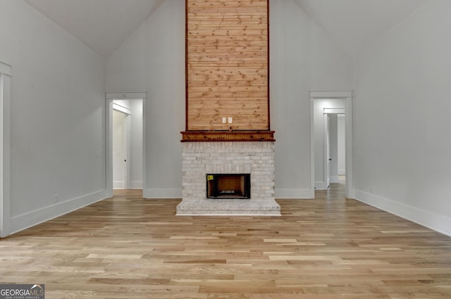 unfurnished living room with high vaulted ceiling, a fireplace, and light hardwood / wood-style flooring