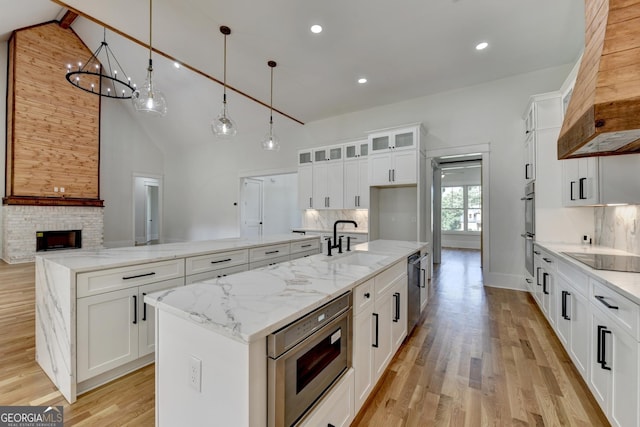 kitchen with decorative light fixtures, white cabinetry, sink, a kitchen island with sink, and stainless steel appliances