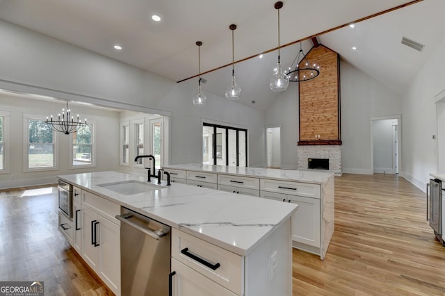 kitchen with appliances with stainless steel finishes, sink, white cabinets, hanging light fixtures, and a spacious island