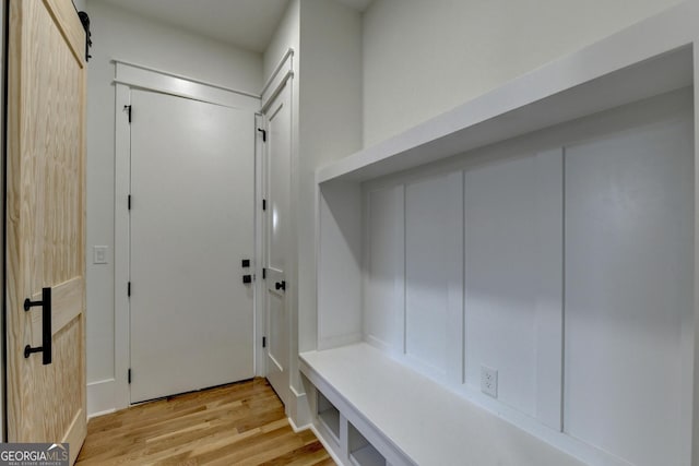 mudroom featuring a barn door and light hardwood / wood-style flooring