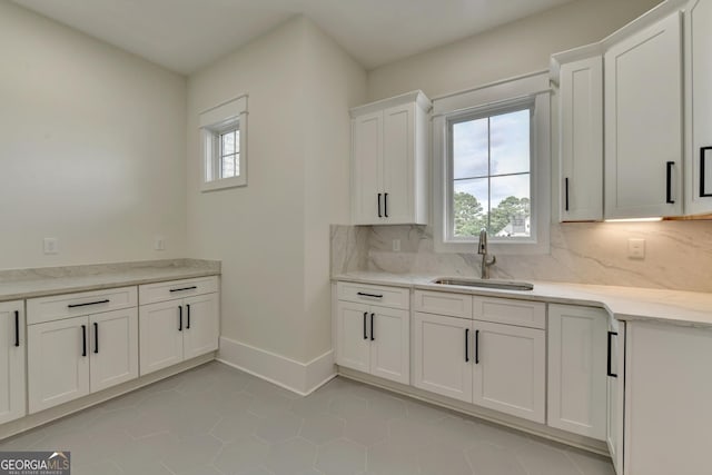 kitchen with a wealth of natural light, sink, decorative backsplash, and white cabinets