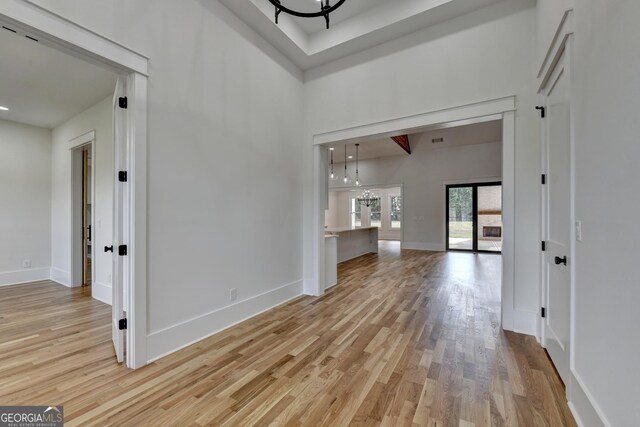 interior space featuring a notable chandelier, light hardwood / wood-style floors, and a high ceiling