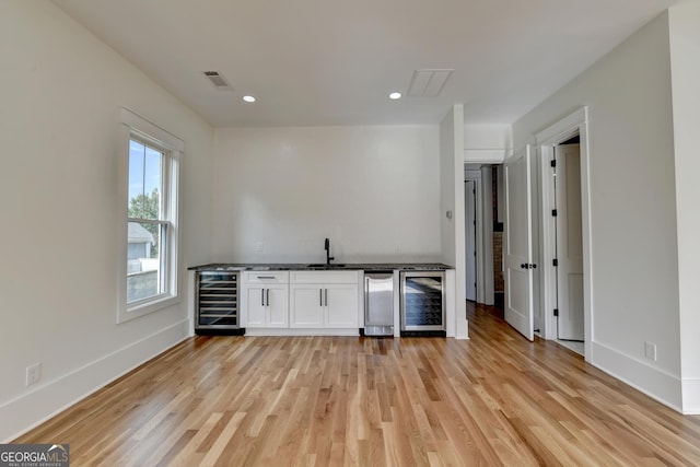 kitchen featuring white cabinets, sink, beverage cooler, and light hardwood / wood-style flooring