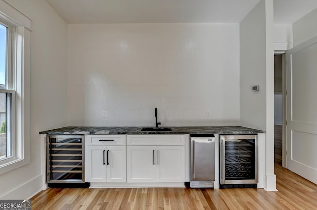 bar featuring wine cooler, sink, white cabinetry, and light hardwood / wood-style floors