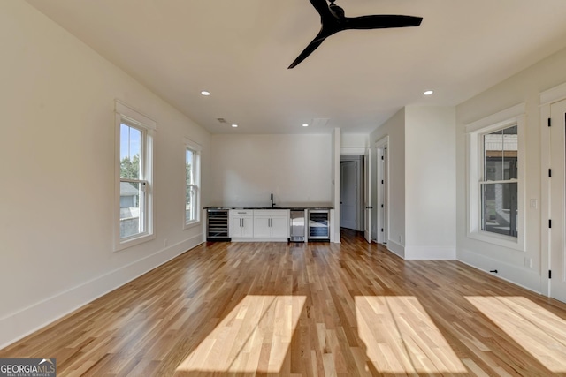 unfurnished living room featuring ceiling fan, beverage cooler, and light wood-type flooring