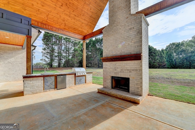 view of patio featuring an outdoor brick fireplace, an outdoor kitchen, a grill, and sink