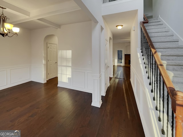 entrance foyer with an inviting chandelier, beam ceiling, and dark hardwood / wood-style floors