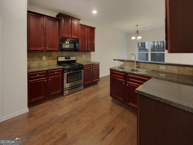 kitchen with dark wood-type flooring, sink, gas stove, tasteful backsplash, and pendant lighting