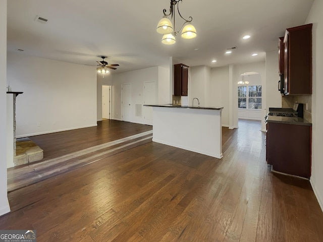 kitchen with ceiling fan with notable chandelier, dark brown cabinets, dark hardwood / wood-style flooring, decorative light fixtures, and kitchen peninsula