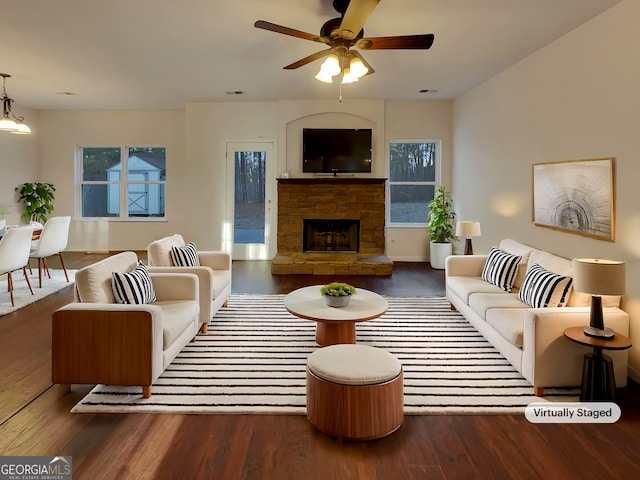 living room featuring ceiling fan, dark hardwood / wood-style floors, and a fireplace