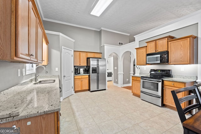 kitchen with light stone counters, sink, crown molding, and appliances with stainless steel finishes