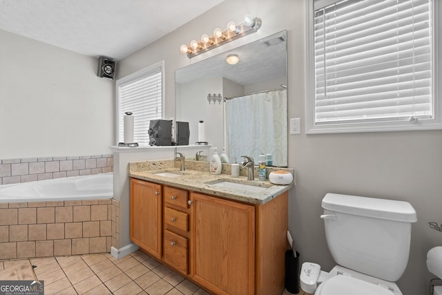 bathroom with tiled bath, tile patterned flooring, vanity, toilet, and a textured ceiling