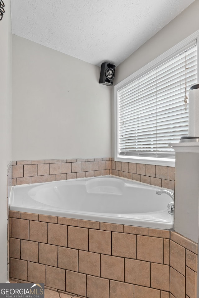 bathroom featuring tiled bath and a textured ceiling